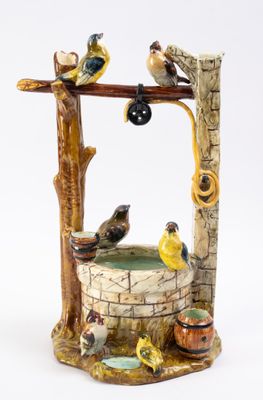 une figurine représentant un puits sur lequel sont perchés des oiseaux