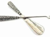 two silver spoons and a spoon rest on a white surface