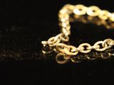 a close up of a gold chain bracelet on a black surface