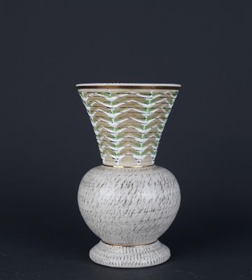 un vase blanc et vert posé sur un socle blanc