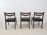 three chairs with black leather upholstered seats in front of a white wall