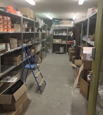 une pièce remplie de cartons, avec une échelle au milieu de la pièce