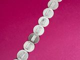 a close up of a silver bracelet on a pink surface