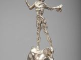 une statue en argent représentant une femme tenant une baguette magique, posée sur un socle en marbre