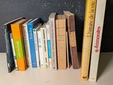 Plusieurs livres sont alignés sur une étagère devant un mur noir