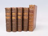 quatre vieux livres sont empilés les uns sur les autres sur une surface blanche
