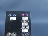 several pairs of earrings are displayed on a black display board