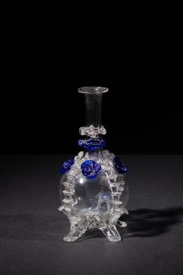 glass vase with blue flowers on it on a black surface