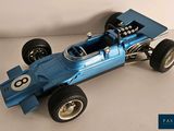 a blue model of a racing car on a white surface
