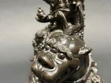 a silver statue of a lion with a dragon on its back