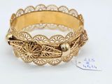 a close up of a gold bracelet on a white surface