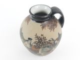 a small vase with a painting on it on a white surface