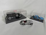 trois petites voitures dans une vitrine posée sur une surface blanche