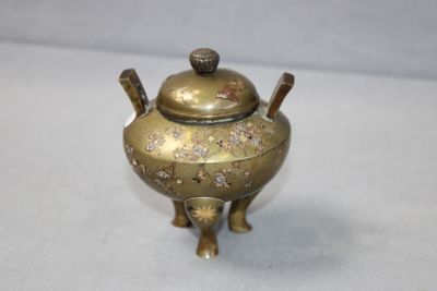 a small brass teapot with a lid on a table