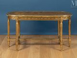 a gold table with a rattan top on a wooden floor