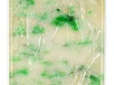 un gros plan d'un savon vert et blanc posé sur une surface blanche