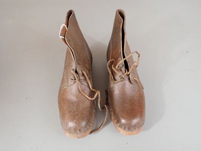 pair of brown leather shoes with laces on them sitting on a white surface