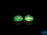 a pair of green emeralds on a black surface