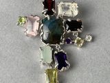 croix en argent ornée de pierres et de gemmes multicolores sur un fond gris