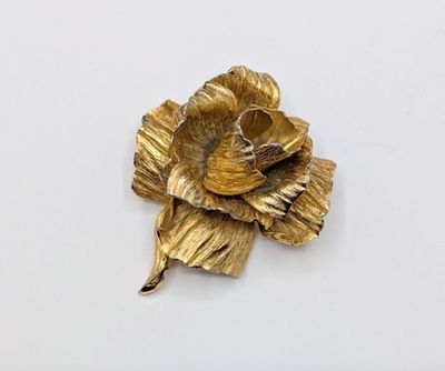 a gold flower brooch on a white surface