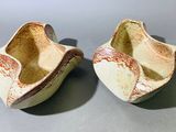 une paire de pantoufles en céramique blanches et marron posées sur une surface grise