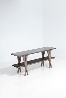 La table est en bois et son plateau est noir.