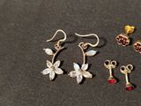 three pairs of earrings and a key on a black surface