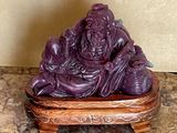 une statue violette posée sur un socle en bois, elle-même posé sur une surface en marbre