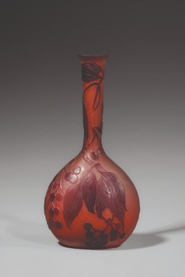 an orange glass vase sitting on top of a table next to a white wall