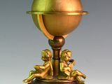 un globe doré posé sur un socle, orné de chérinsils