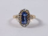 a close up of a blue sapphire and diamond ring on a white surface