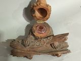 a statue of a bird sitting on top of a piece of wood
