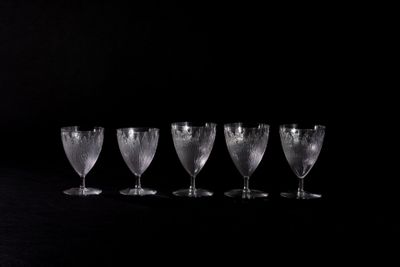 four empty wine glasses are lined up in a row on a black surface