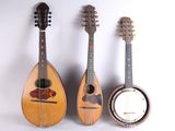 trois guitares et un banjo sont alignés contre un mur blanc