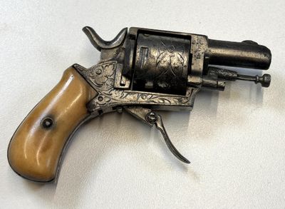 un petit revolver avec une crosse en bois posé sur une surface blanche