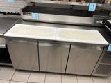 stainless steel counter top in a restaurant kitchen with a lot of food on the shelves