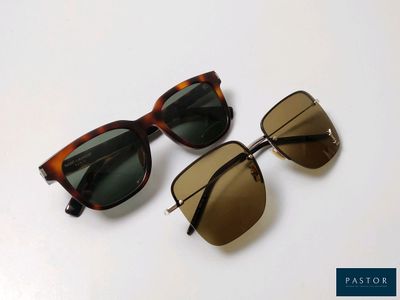 two pairs of sunglasses sitting on top of each other on a white surface