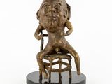 bronze statue of a woman sitting on a stool with her legs crossed