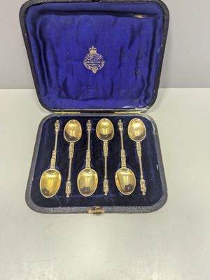 six cuillères en argent dans un coffret posé sur une table