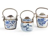 trois vases bleus et blancs munis d'anses, posés sur un fond blanc