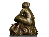 bronze statue of a woman sitting on a rock with her hands on her knees