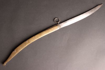 un gros plan d'un couteau posé sur une table, sur lequel est posé une bague