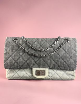 a grey and white quilted bag with a chain strap