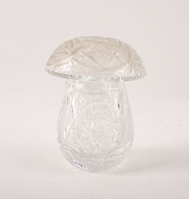 un vase en verre transparent surmonté d'un champignon, posé sur une surface blanche