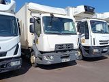 several white trucks are lined up in a row in a parking lot