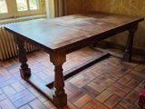a large wooden table in a room with a brick floor