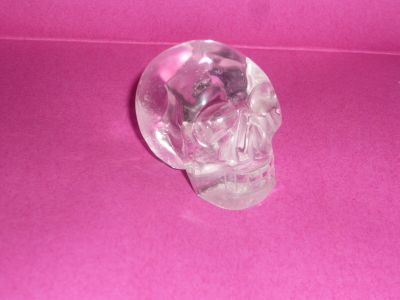 a crystal skull sitting on a pink surface