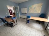 une pièce avec un bureau, des chaises et une carte accrochée au mur