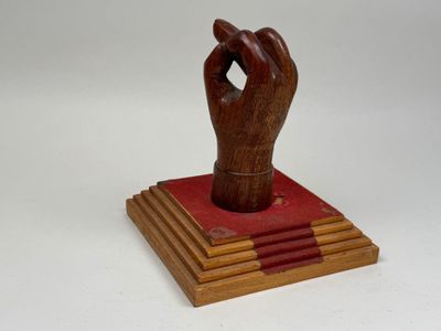 sculpture en bois représentant une main tenant un livre sur fond blanc