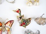 many different types of brooches and jewelry on the table